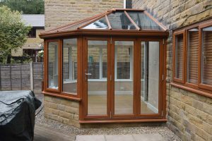 A conservatory installation using brick base and oak colour uPVC windows and doors