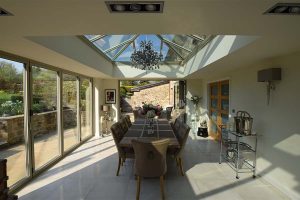 An orangery with a large dining room table and large glass roof